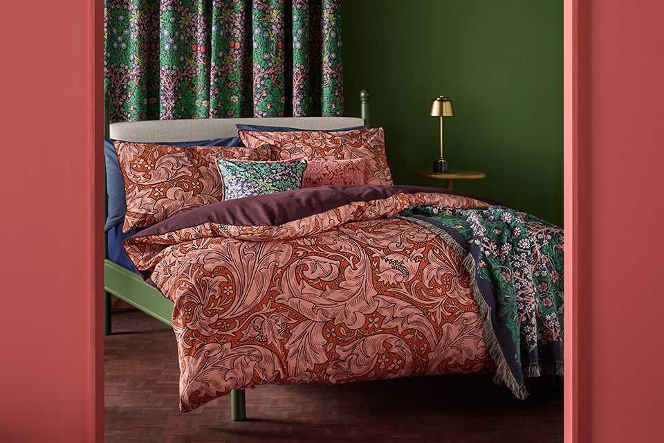 Red patterned paisley bedding with green floral throw in bold and daring colours.
