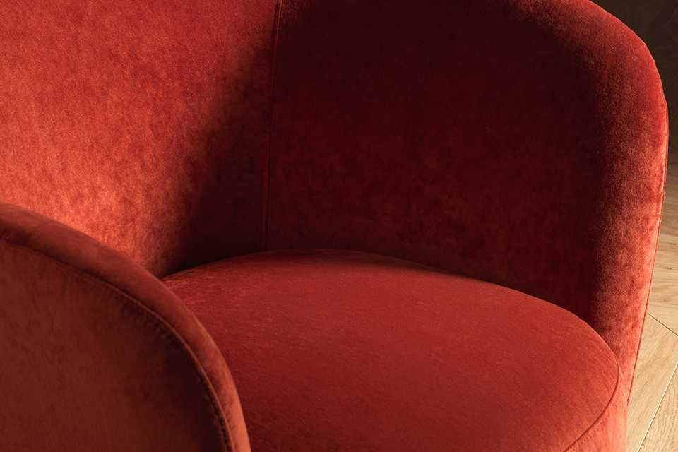 Orange velvet curved accent chair.