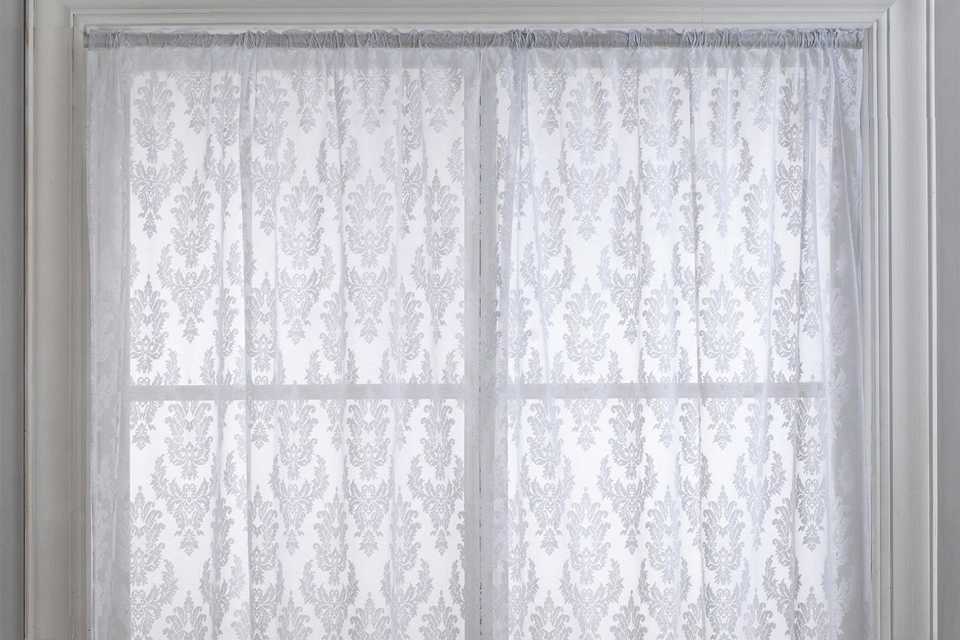 An Argos Home Damask net pencil pleat white floral curtain on a curtain track.