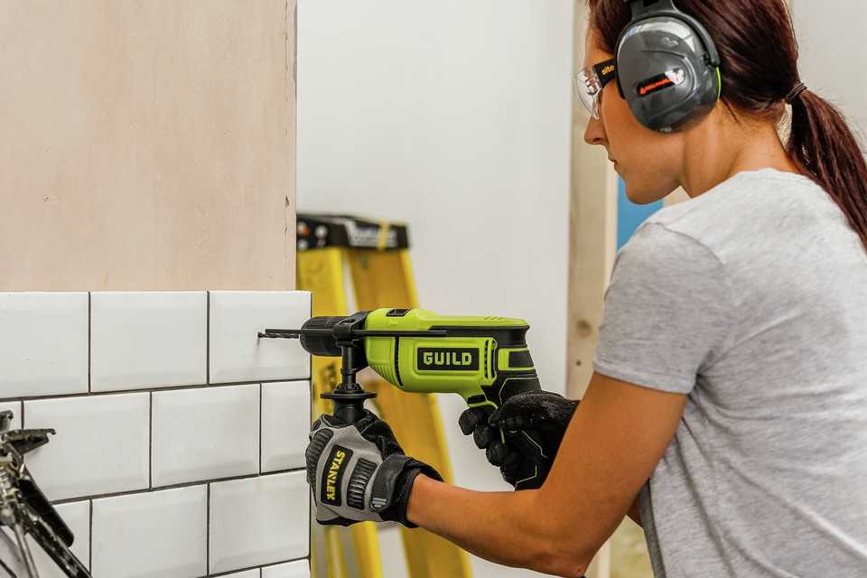 A woman using Guild PDI800G2 Corded Impact Drill - 800W.