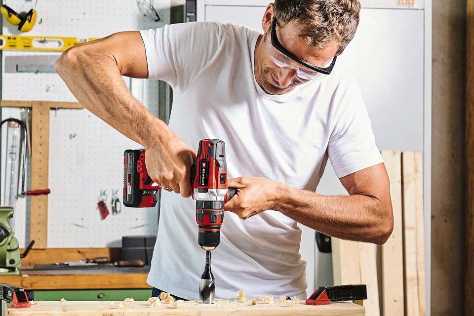 A man using Einhell Power X-Change Cordless Combi Hammer Drill - 18V.