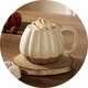 Cream shaped pumpkin mug placed onto a wooden coaster on an oak dining table.