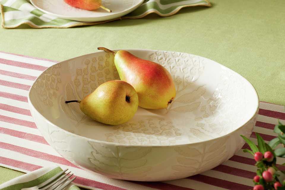 A white Habitat x Sanderson National Trust serving bowl with pears in it placed on a table.