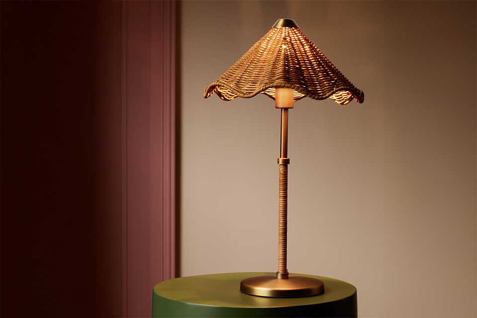 A Habitat rattan table lamp placed on a table.
