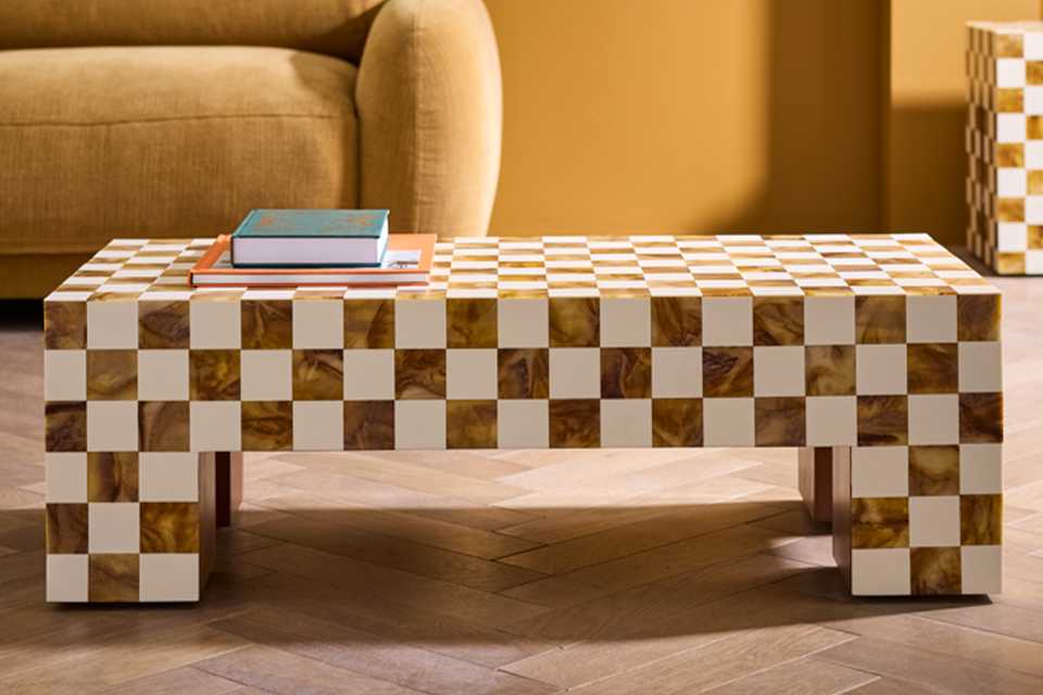 Yellow velvet sofa with checker coffee table in living room.