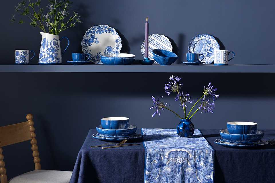 Blue dining room with morris tablware in blue chine floral print and blue tablecloth.