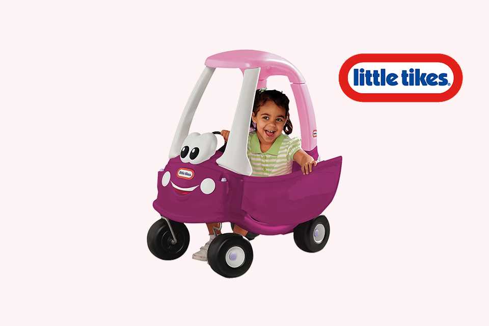 A girl sitting on a Little Tikes cozy coupe.