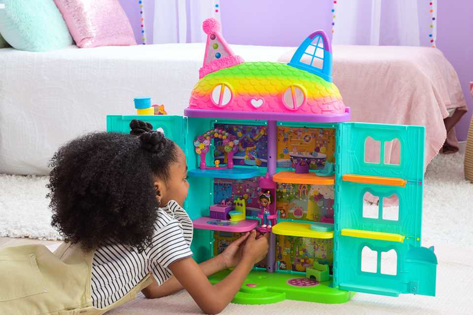 A little girl playing with a Gabby dollhouse set in her bedroom.