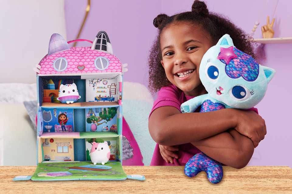 A little girl hugging a Gabby's Dollhouse plush toy.