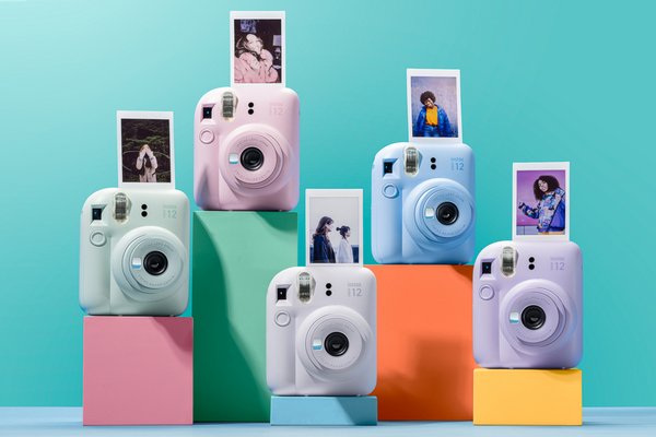Five instax mini 12 instant cameras in green, pink, white, blue and purple with mini film.