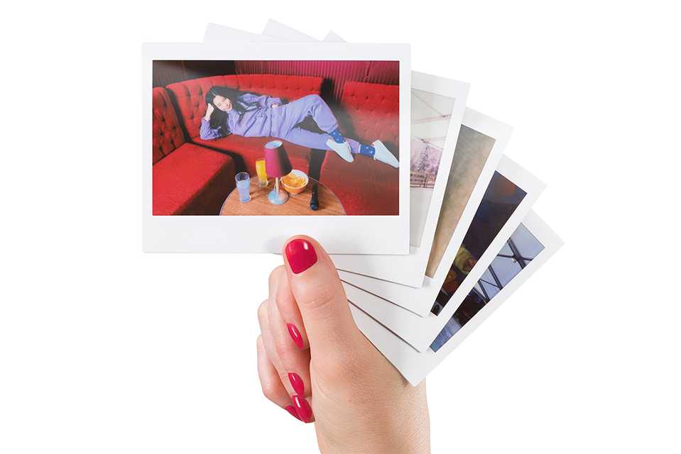 A person holding a bunch of photos printed on instax™ WIDE film.