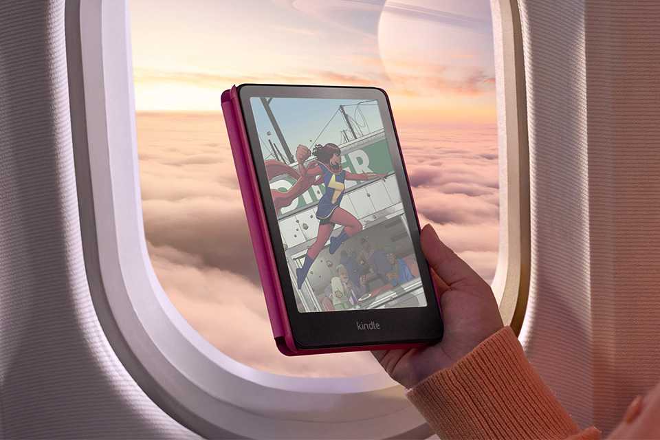 A person holding a Kindle Colorsoft e-reader against an airplane window.