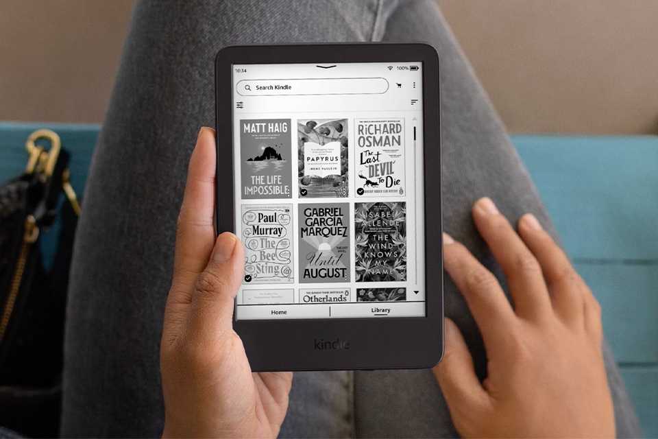 A person scrolling through e-book gallery on a black Kindle 2024 e-reader.