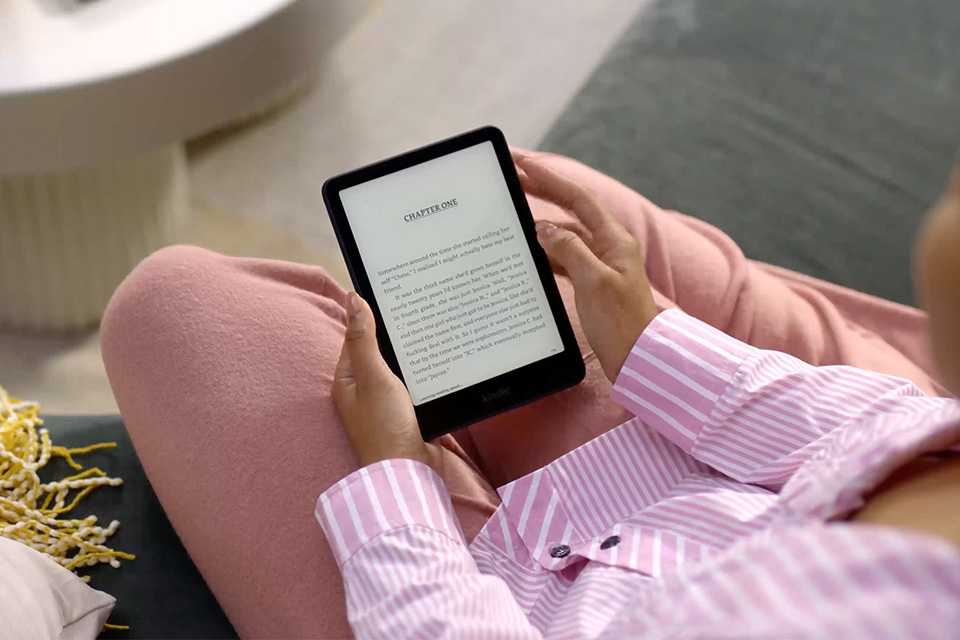 A woman reading an e-book on her Kindle Paperwhite e-reader.