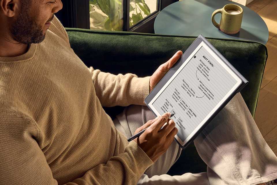 A man writing notes using a pen on his Kindle Scribe e-reader.