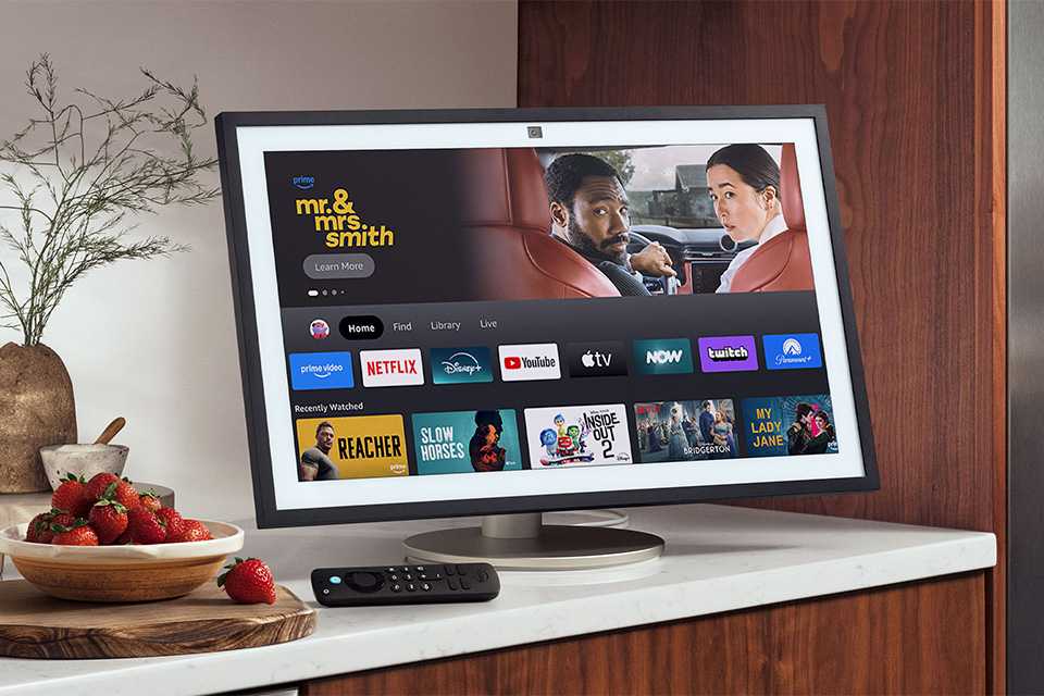 Amazon Echo Show 21 smart display with other things on a table top.