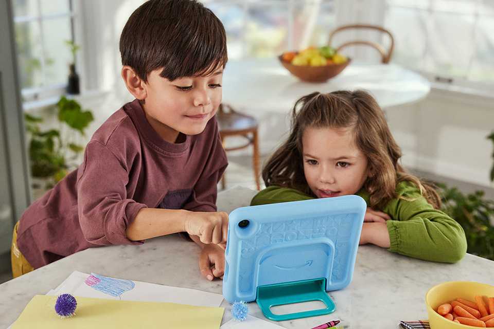 A little boy and a girl browsing content on their blue Amazon Fire kids' tablet.