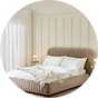Cloud cream lined bedframe ith white bedding in large room painted white.