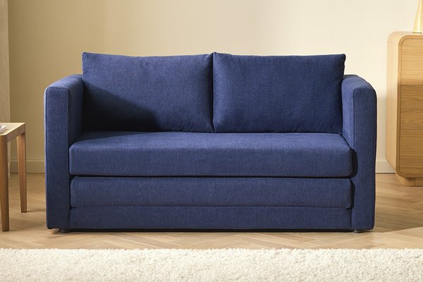 A split image with a blue Argos Home fabric sofa bed placed in a room on one side and opened out on the other.