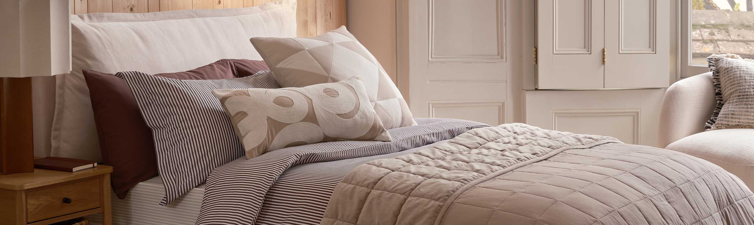 A cosy bed made with a duvet and some pillows.