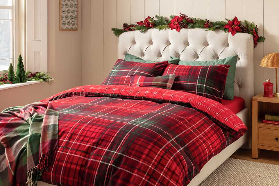 A classic green and red checkered bed linen on a white bed in a bedroom.