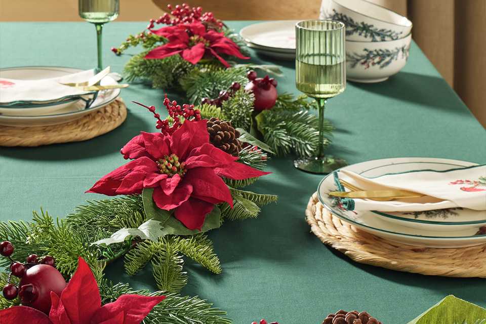 Christmas table decorated with candles, greenery and festive ornaments.