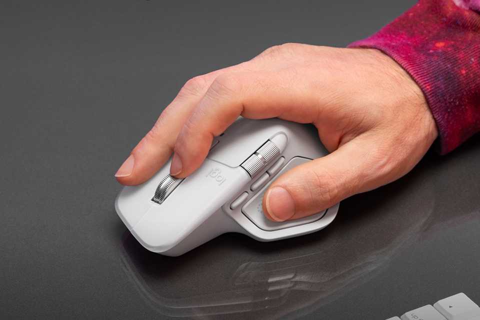 A person using a Logitech wireless mouse for Mac in pale grey.