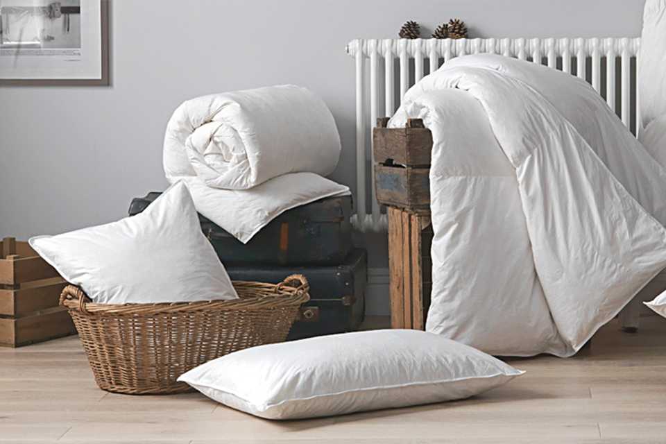 Two rolled up duvets and two pillows in a room.