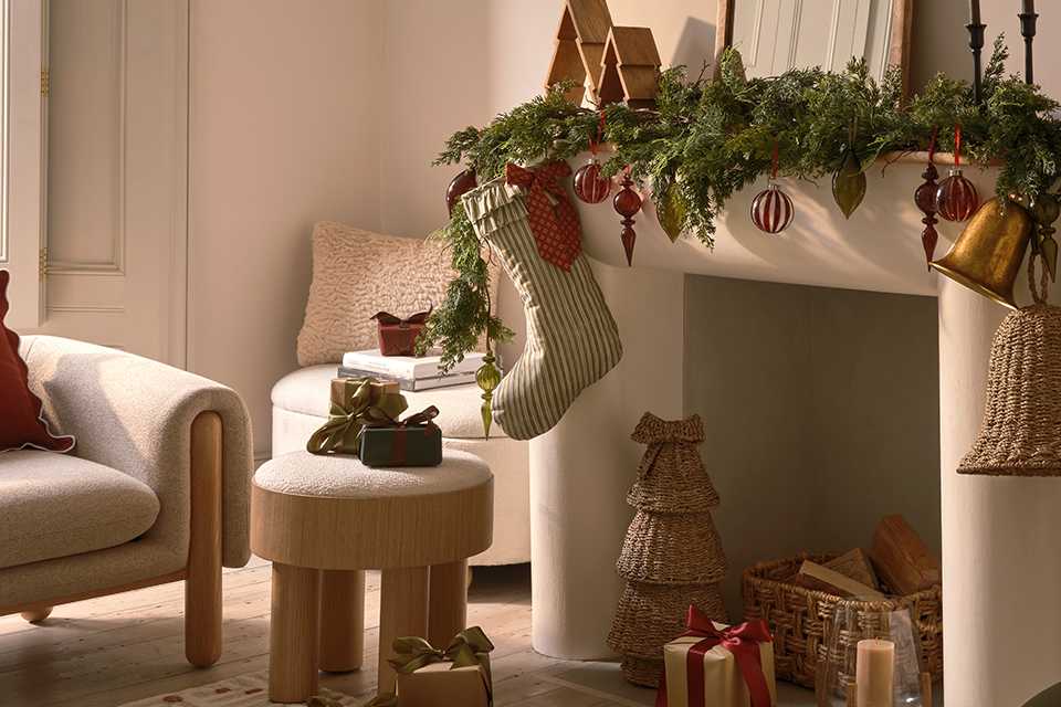 A living room decorated with Christmas decorations, a stocking over the fireplace and some gifts placed all around.