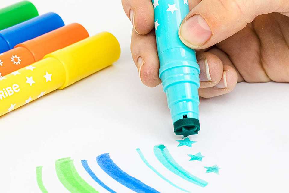 A child using colourful sketch pens to draw on a sheet of paper.