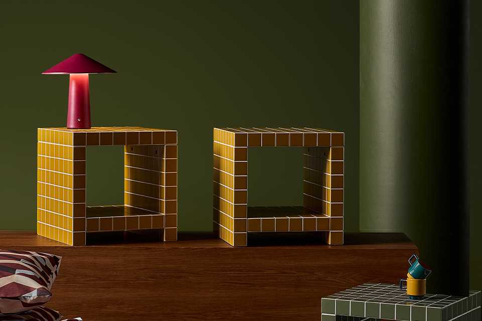 Three check patterned side tables and a red table lamp on top of one.