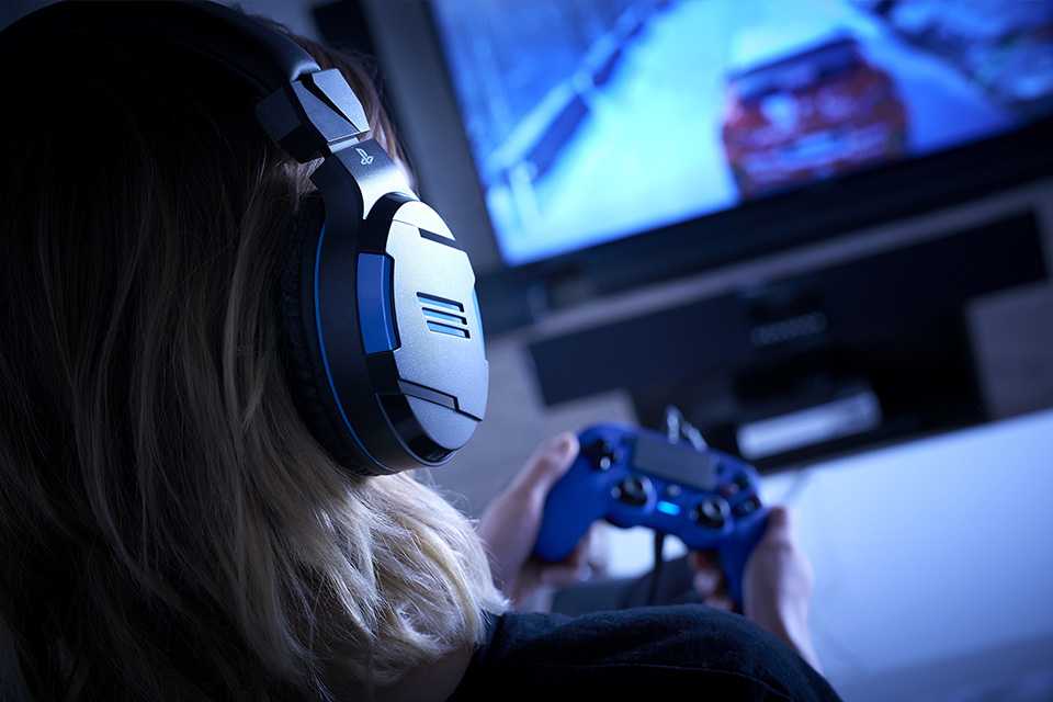 A girl playing video game on a console wearing headsets.