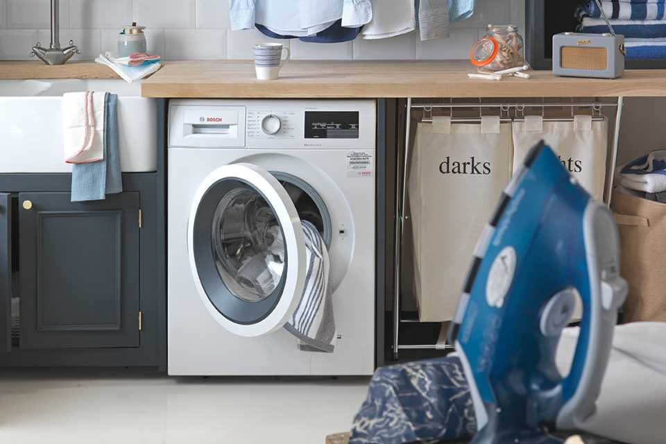 A white washing machine in a utility room under a wooden counter.