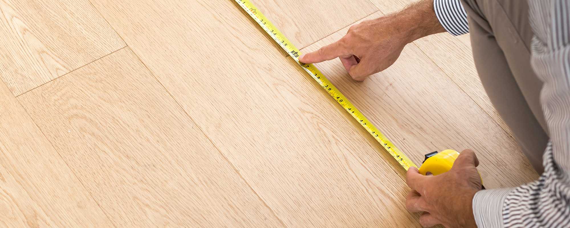 A person using tape measure to measure the floor size.