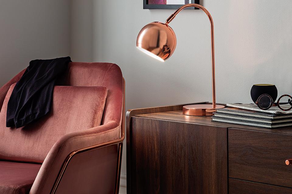 An elegant table lamp positioned on a sideboard next to an armchair.