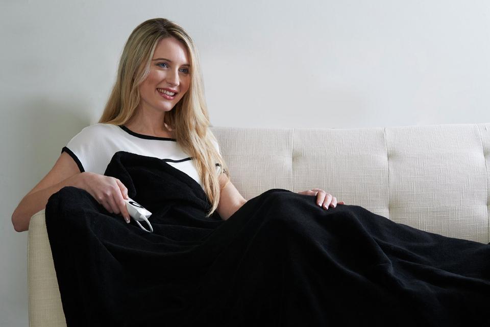Woman resting on sofa with electric blanket.