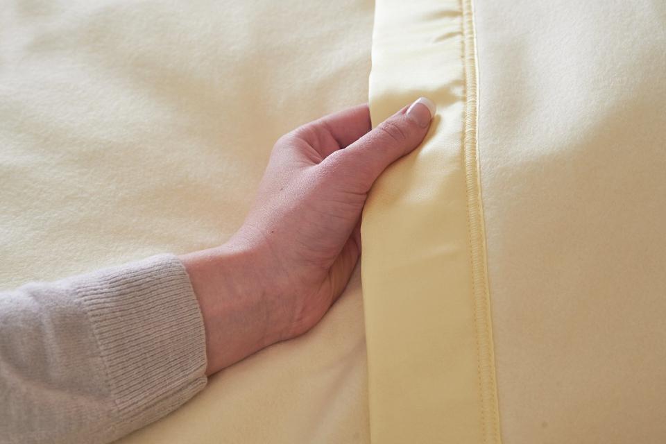 Hand touching electric blanket trim.
