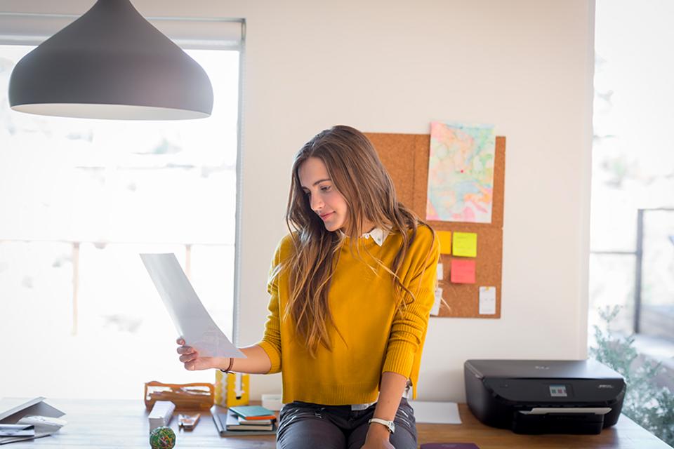 Woman in home office looking at a printout.