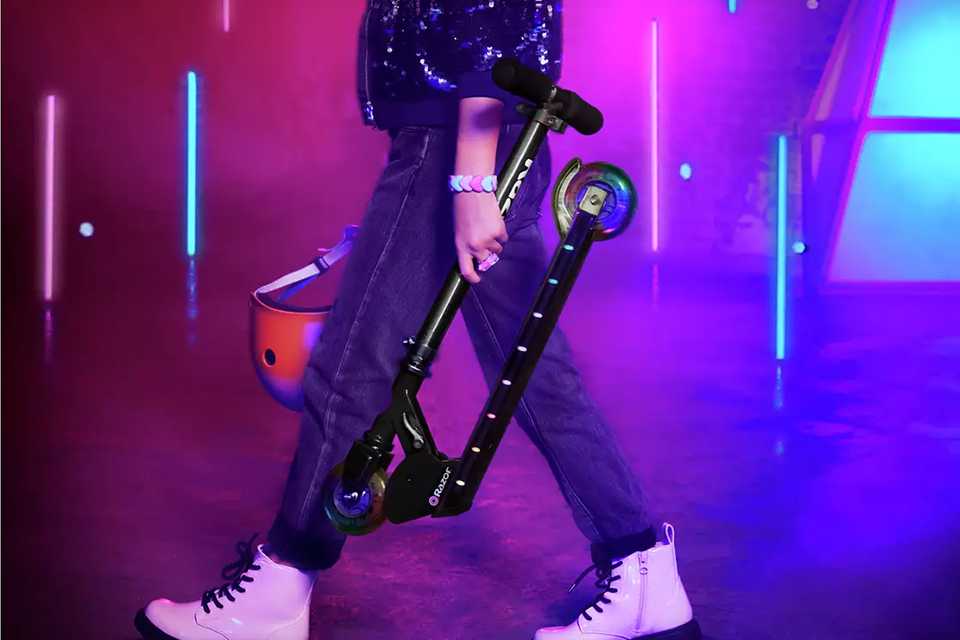 A teen holding a folding scooter.