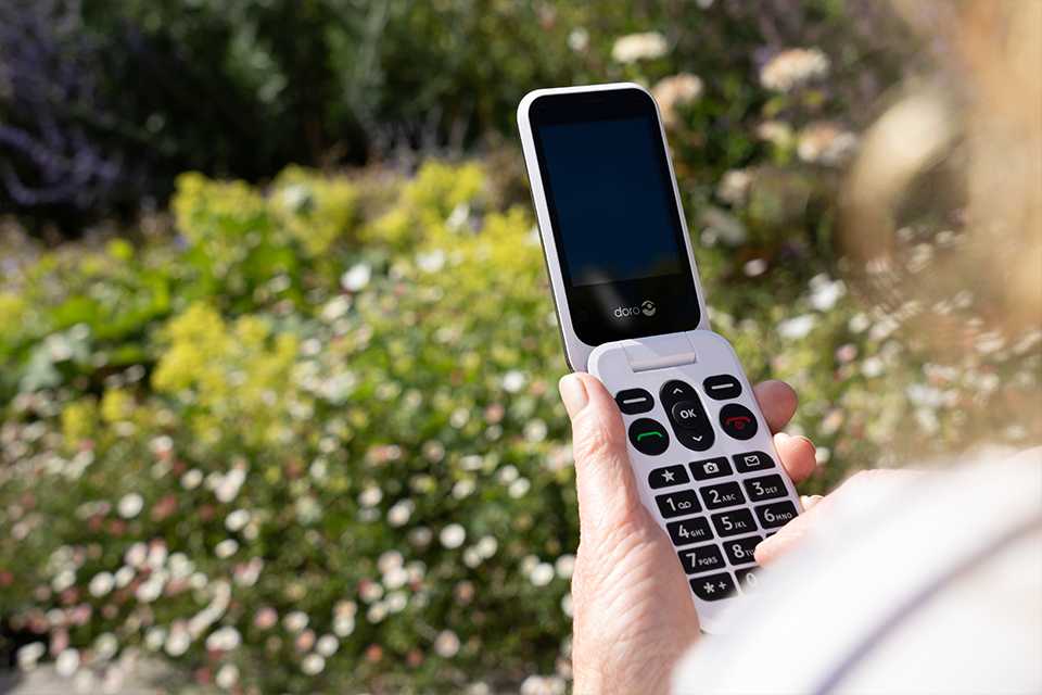 A hand holding an open Doro Leva L20 flip phone.