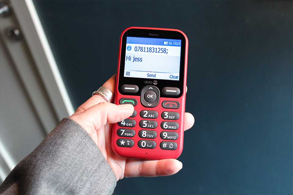 A lady holding a red Doro Leva E10 feature phone.