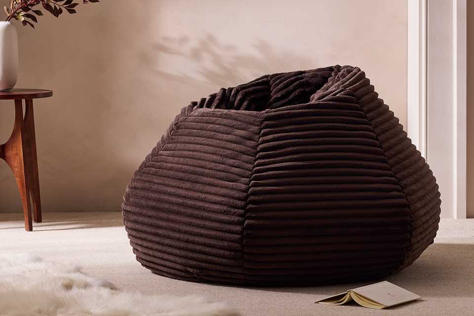 Brown bean bag in living room next to wooden side table.