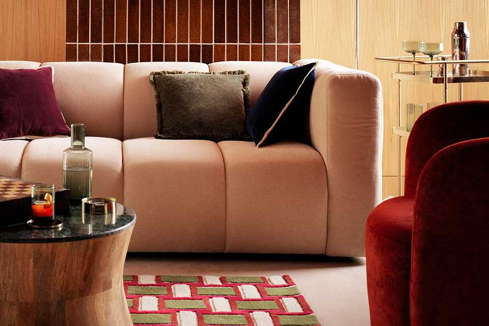 White bubble sofa in neutal living room and warm toned accent chairs and cushions with wooden coffee table in front of sofa.
