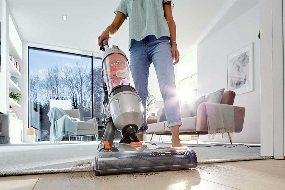 A below shot of a man using corded vacuum cleaner.