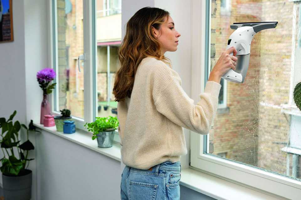 A woman using a window vacuum to clean her windows.