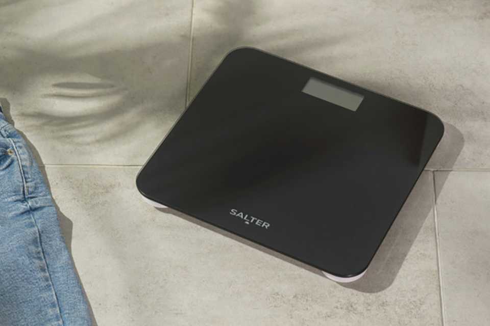 A Salter battery-free bathroom scale on the floor of a bathroom.