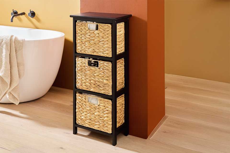 Black freestanding bathroom storage unit beside a bathtub.