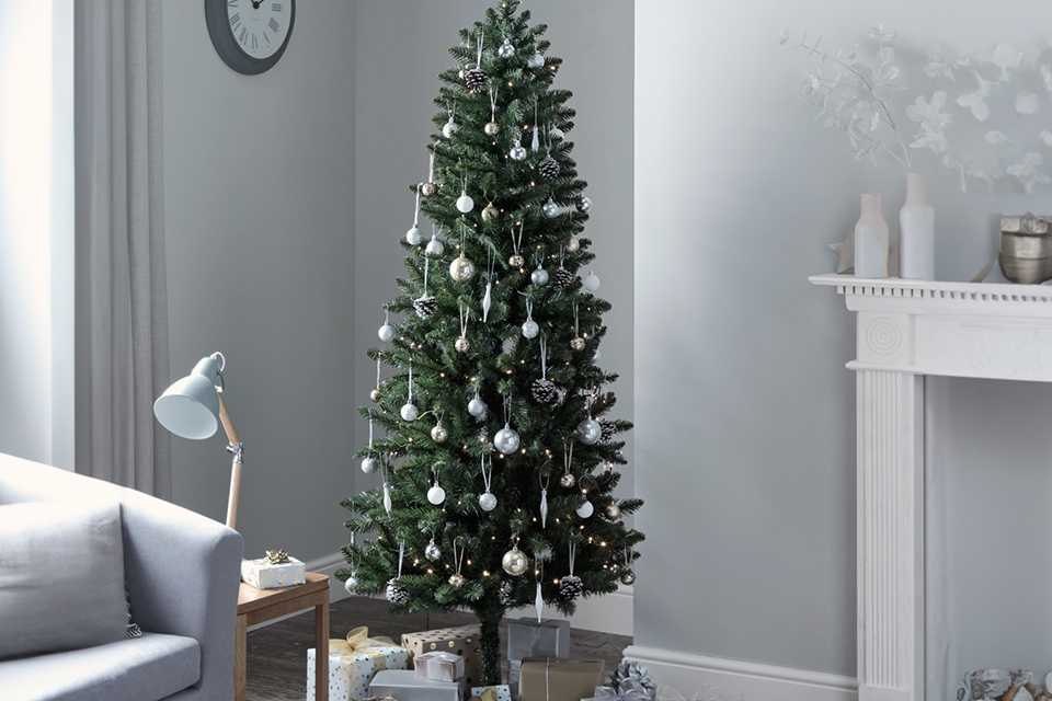 A Habitat 6ft slim evergreen tree with gifts under it in a living room.