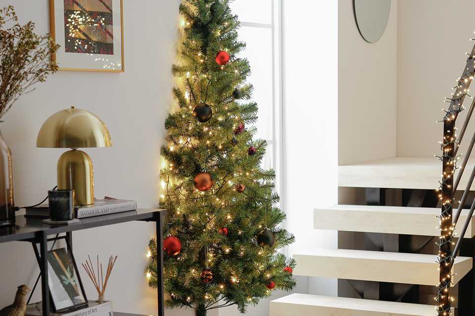 A Habitat 6ft half Christmas tree decorated in a living room with gifts under it.