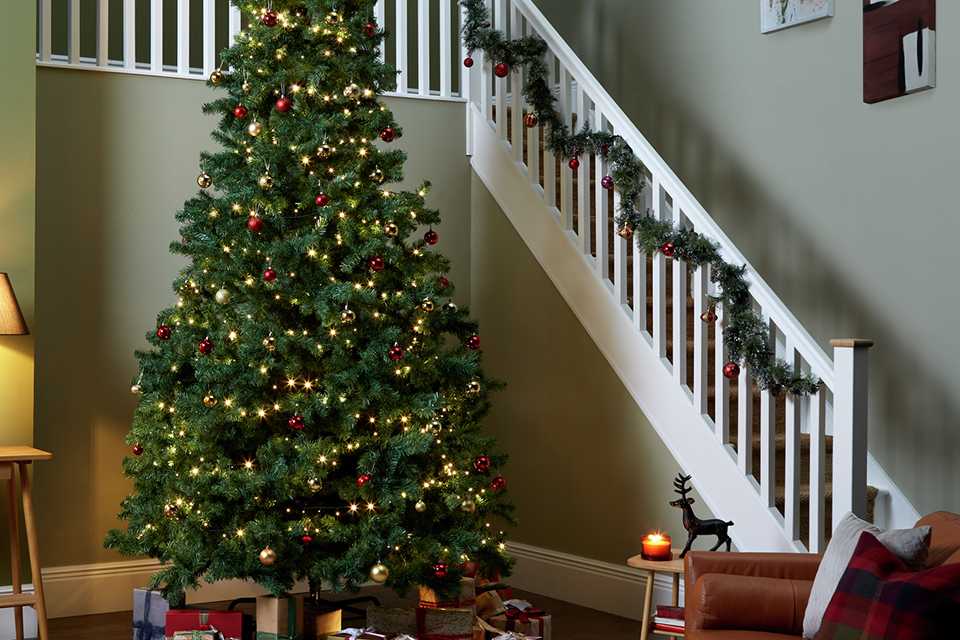 A Habitat 12ft Christmas tree with red and gold decorations in a living room.
